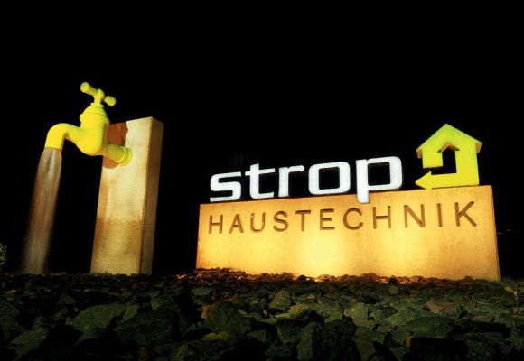 Firmenlogo Strop Haustechnik GmbH & Co. KG im Dunkeln beleuchtet.